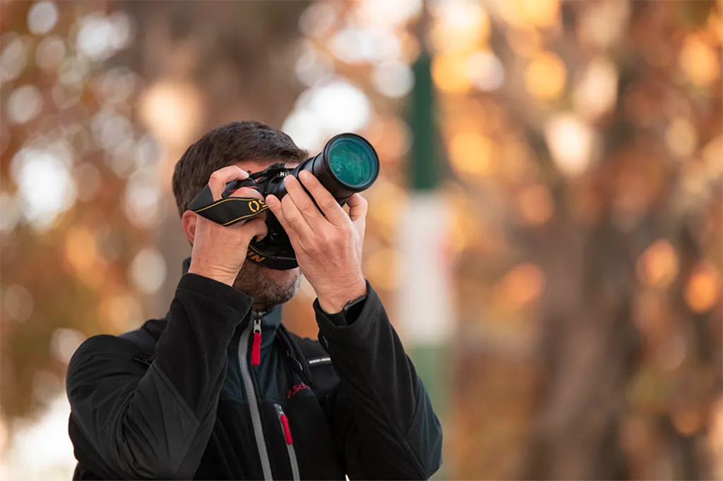 Photographe tenant un téléobjectif, arrière-plan automnal